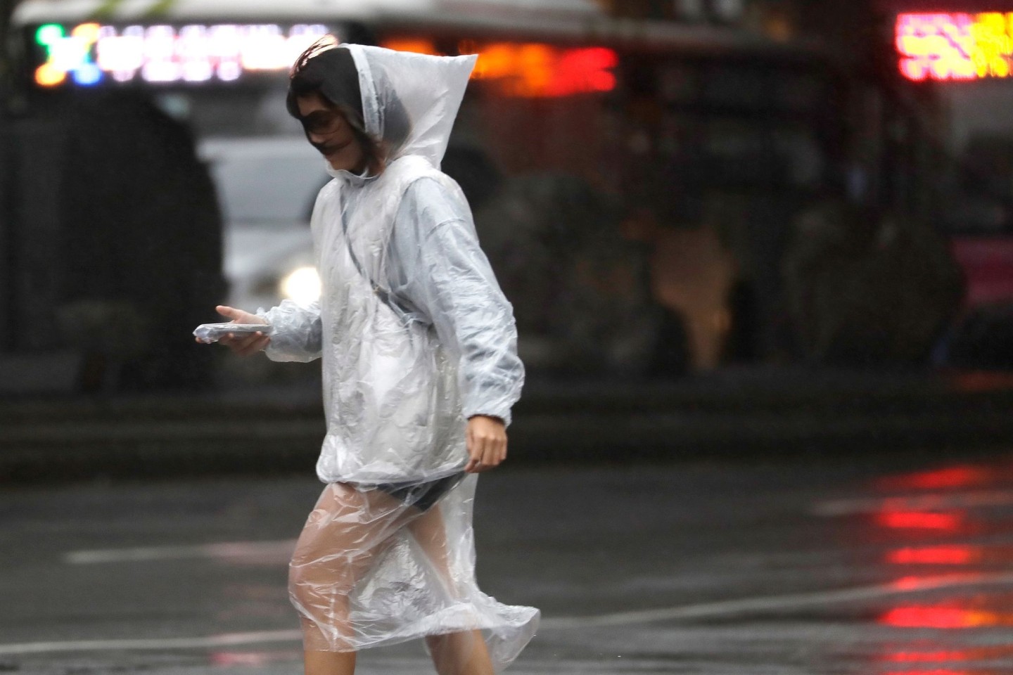 Eine Frau läuft bei Regen und Wind durch Taipeh.