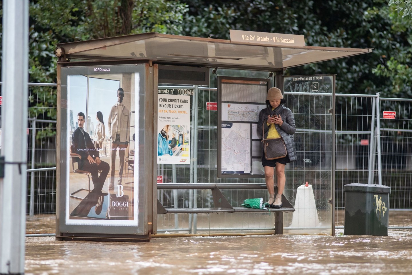 Wasser umschließt eine Bushaltestation in Mailand.